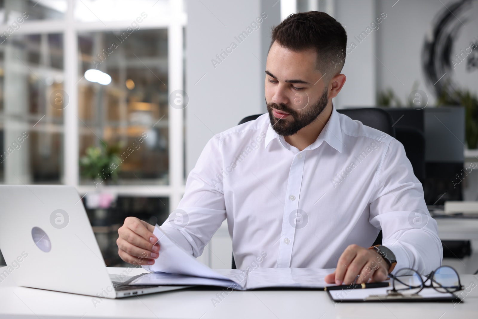 Photo of Handsome man working at table in office. Lawyer, businessman, accountant or manager