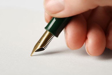 Photo of Woman with fountain pen above light paper, closeup