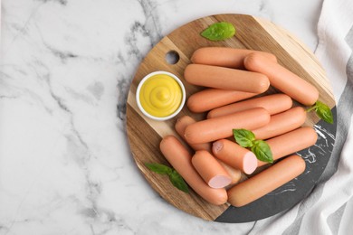 Photo of Delicious boiled sausages, sauce and basil on white marble table, top view. Space for text