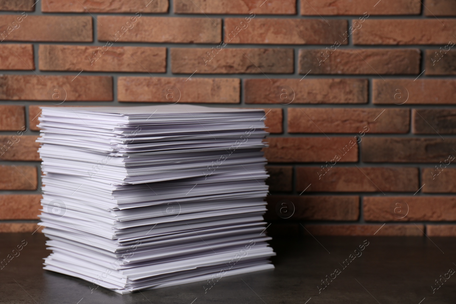 Photo of Stack of paper sheets on black table. Space for text