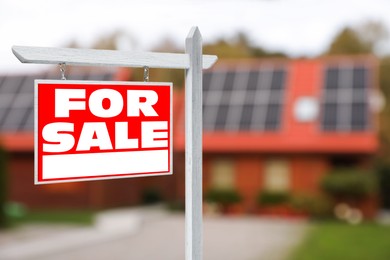 Sale sign near beautiful house outdoors. Red signboard with words