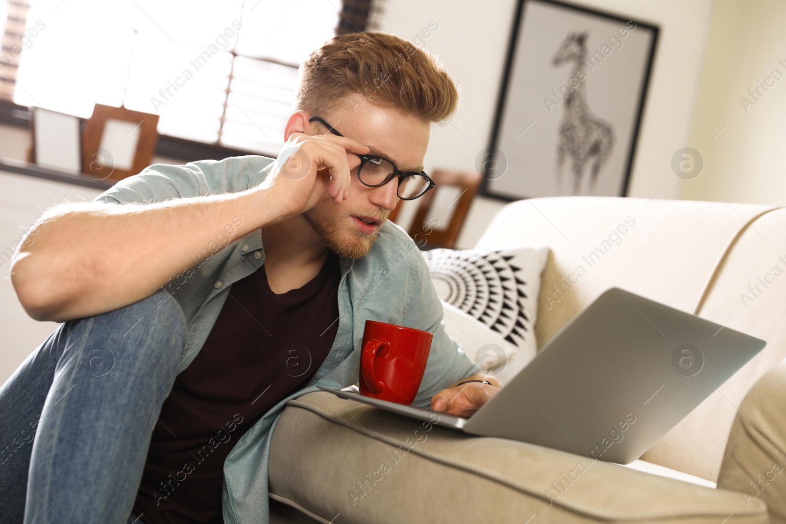 Photo of Young man using laptop in living room