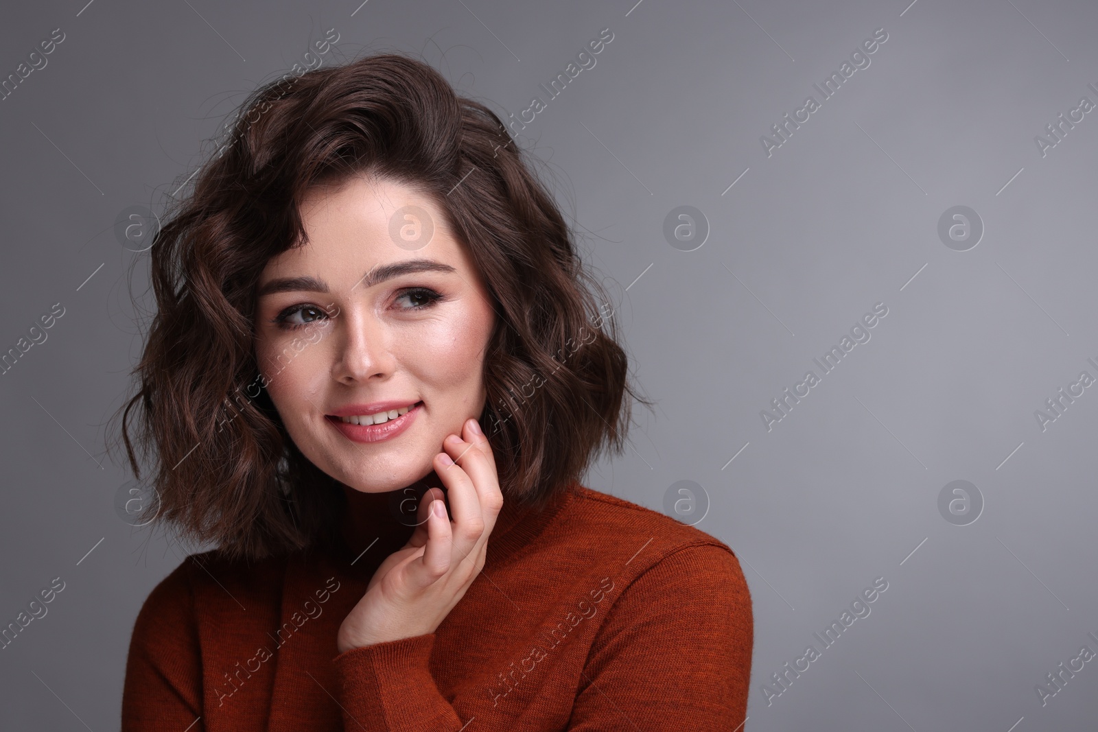 Photo of Portrait of beautiful young woman with wavy hairstyle on grey background. Space for text