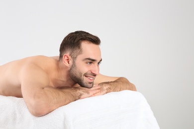 Handsome man relaxing on massage table against white background. Spa service
