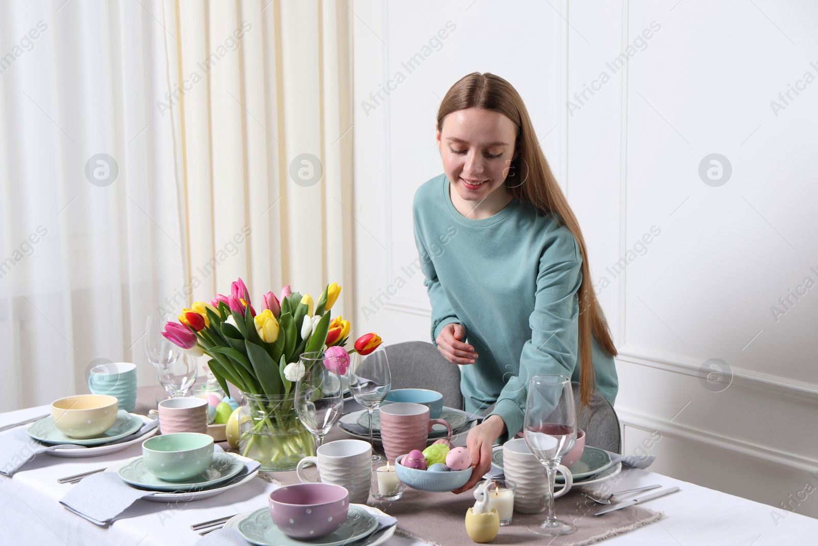 Photo of Woman setting table for festive Easter dinner at home