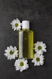 Fresh mouthwash in bottle and flowers on dark textured table, top view