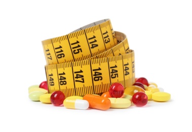 Weight loss pills and measuring tape on white background