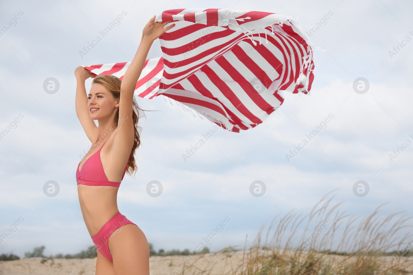 Photo of Beautiful woman in bikini with beach towel on sand