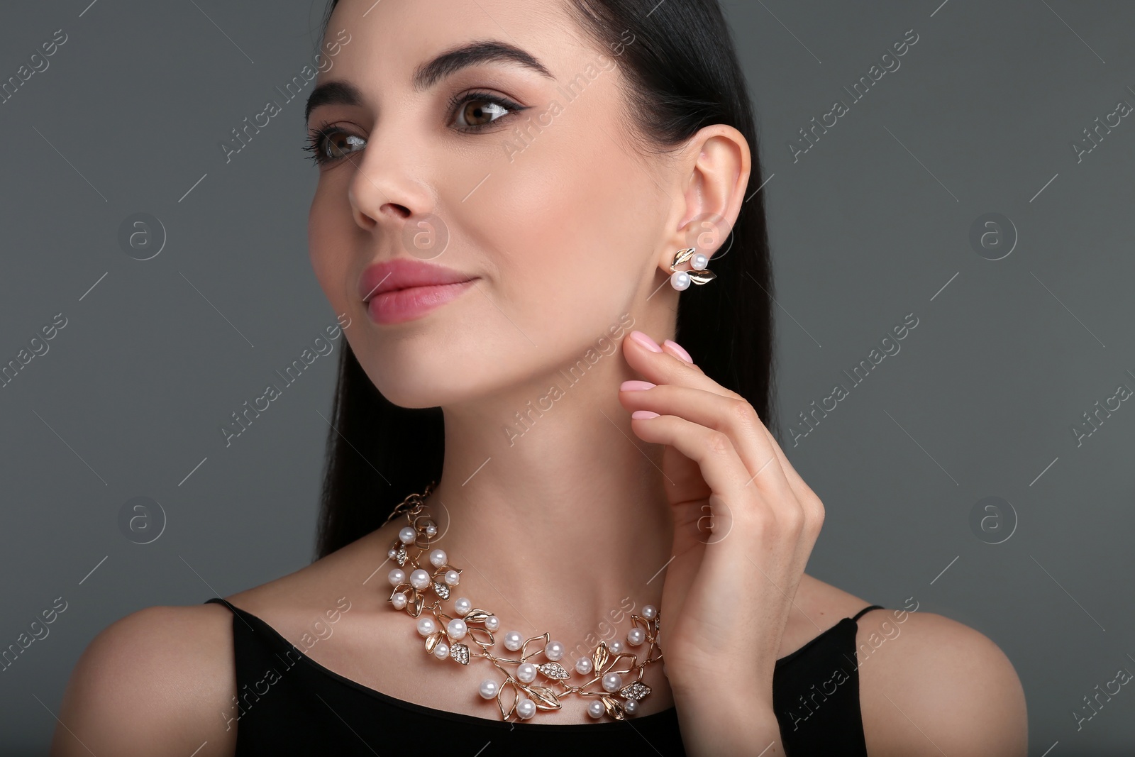 Photo of Beautiful young woman with elegant jewelry on dark grey background