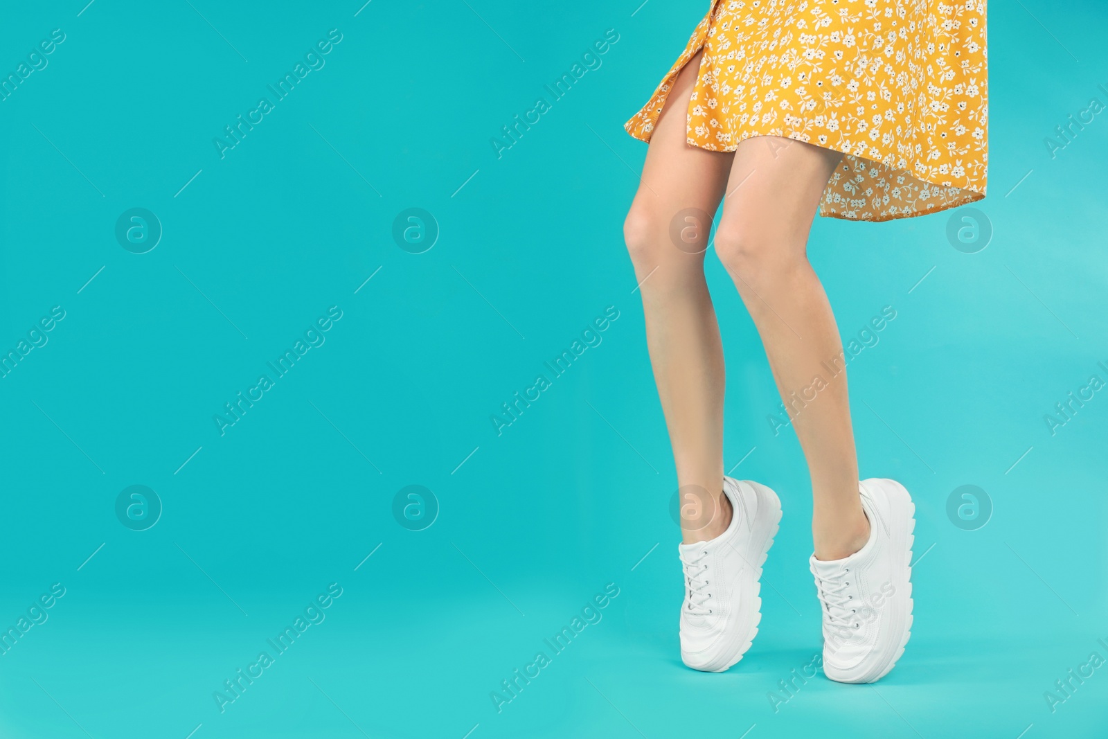 Photo of Woman in stylish sport shoes on light blue background. Space for text