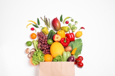 Paper bag with assortment of fresh organic fruits and vegetables on white background, top view