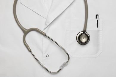 Photo of Stethoscope on white medical uniform, top view