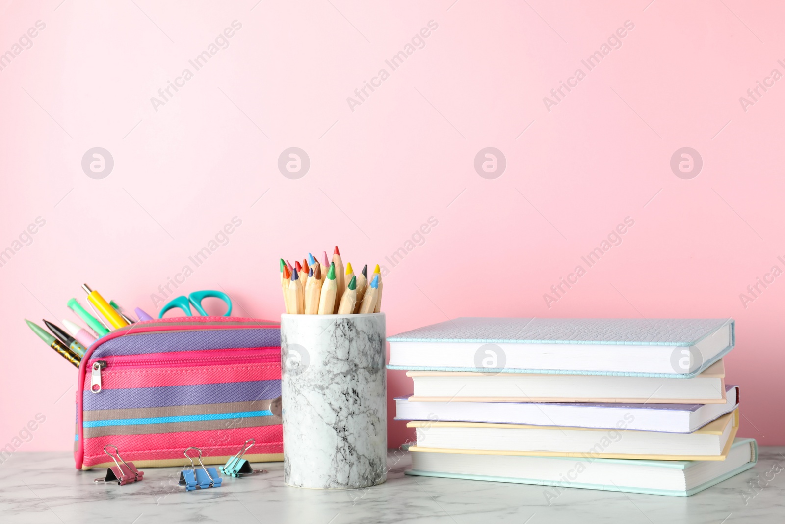 Photo of Stack of hardcover books and stationery on table against color background. Space for text