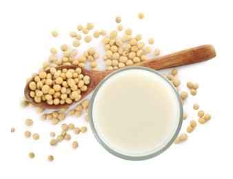 Glass of fresh soy milk and spoon with beans on white background, top view