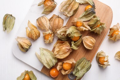Ripe physalis fruits with dry husk on white wooden table, flat lay