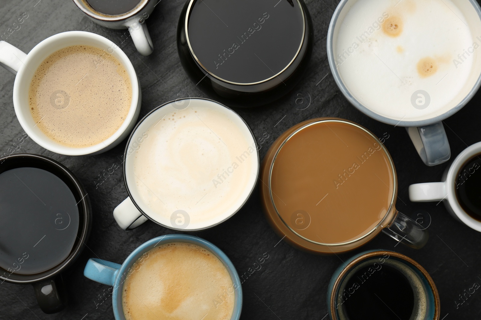 Photo of Different coffee drinks in cups on dark textured table, flat lay