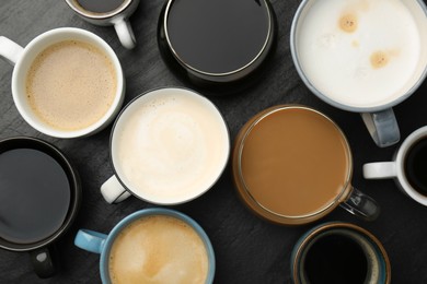Photo of Different coffee drinks in cups on dark textured table, flat lay