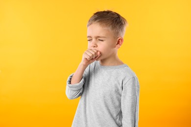 Photo of Sick boy coughing on yellow background. Cold symptoms