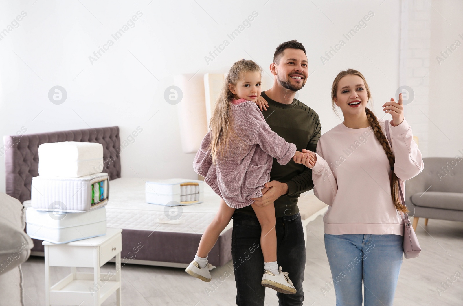 Photo of Happy family looking for mattress in furniture store