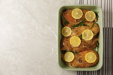 Chicken breasts with lemon and rosemary on grey table, top view. Space for text