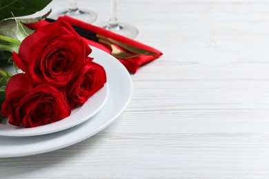 Photo of Beautiful place setting with dishware and roses for romantic dinner on white wooden table. Space for text