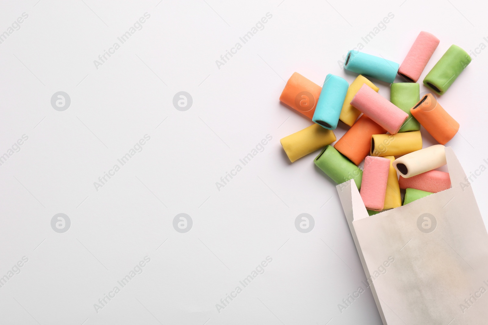 Photo of Paper bag with tasty liquorice candies on light background, top view. Space for text