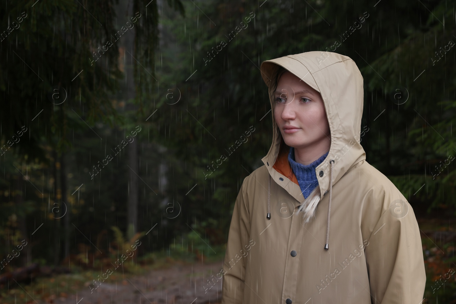 Photo of Young woman with raincoat in forest under rain