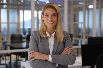 Photo of Smiling woman with crossed arms in office. Lawyer, businesswoman, accountant or manager