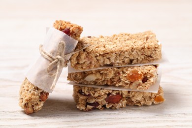Photo of Tasty granola bars on white wooden table, closeup