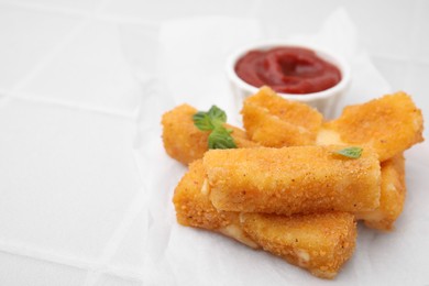 Photo of Tasty fried mozzarella sticks with basil leaves and ketchup on white tiled table, closeup. Space for text