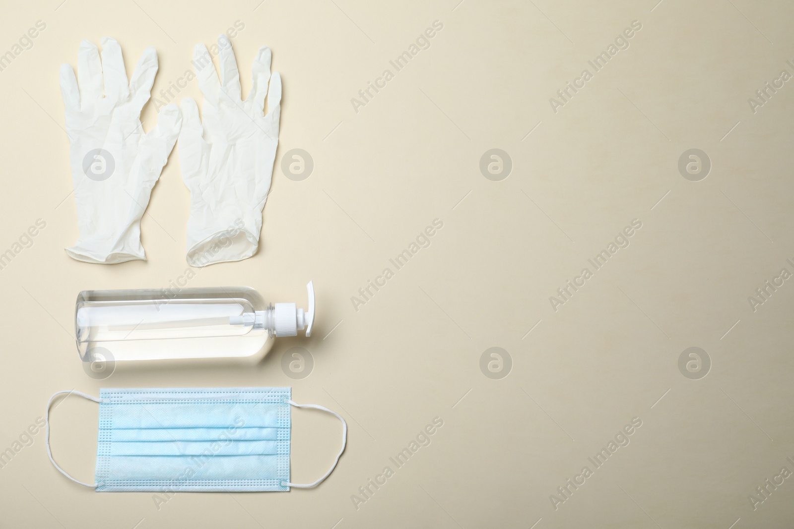 Photo of Medical gloves, mask and hand sanitizers on beige background, flat lay. Space for text