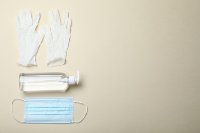 Medical gloves, mask and hand sanitizers on beige background, flat lay. Space for text