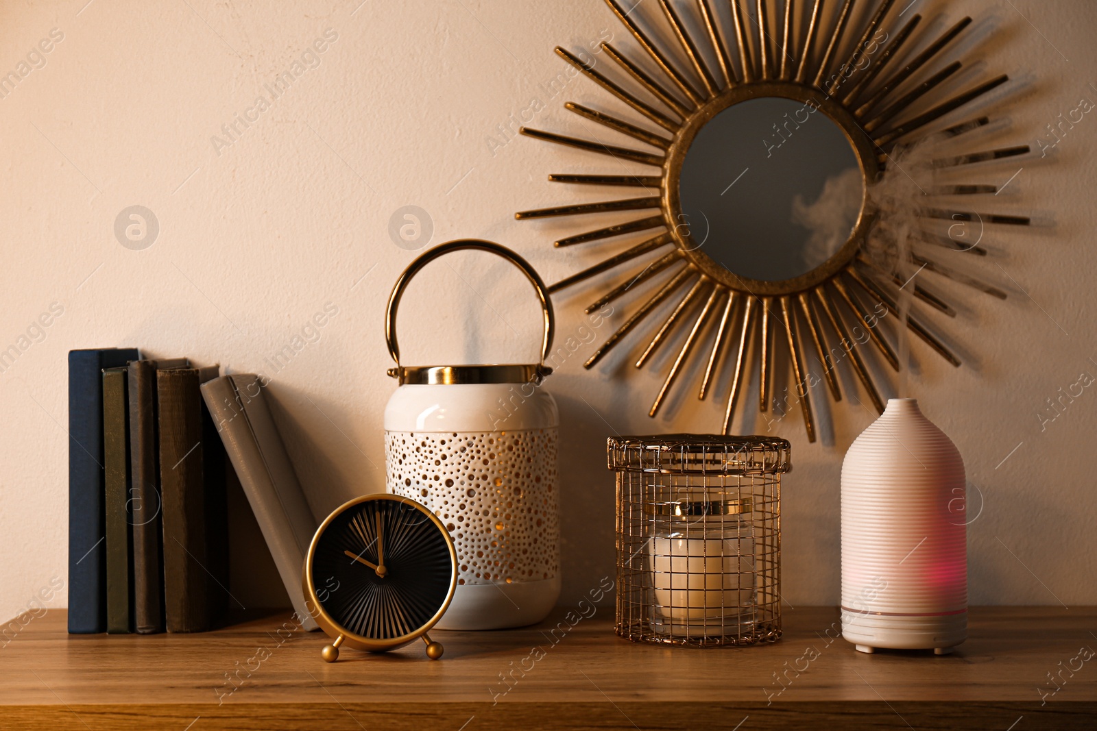 Photo of Aroma oil diffuser, books and decor element on shelf indoors