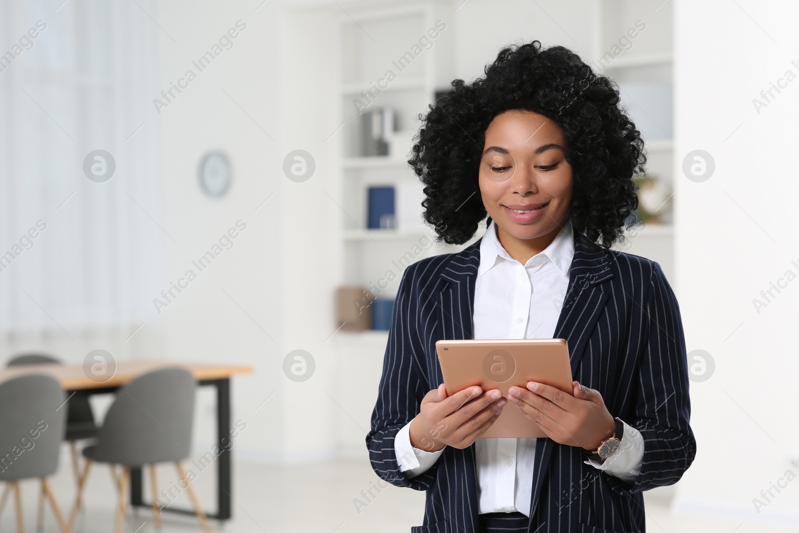 Photo of Smiling young businesswoman using tablet in office. Space for text