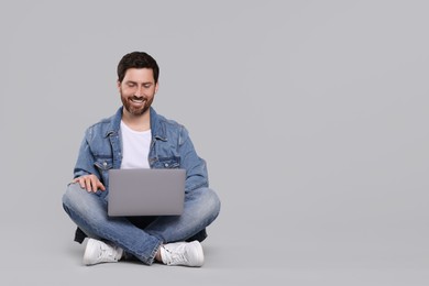 Photo of Happy man with laptop on light grey background. Space for text