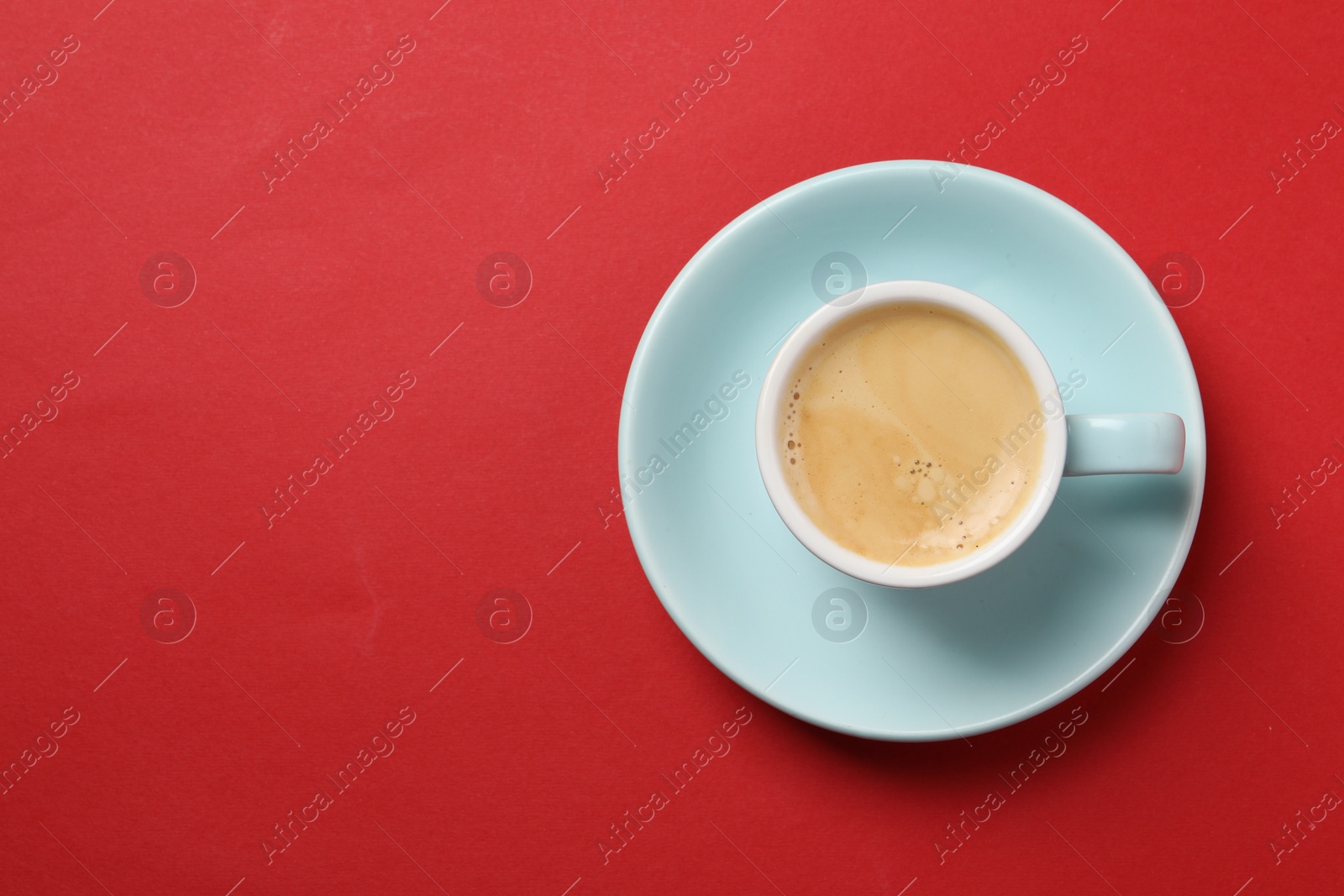 Photo of Aromatic coffee in cup on red background, top view. Space for text