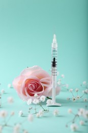 Cosmetology. Medical syringe, rose and gypsophila flowers on turquoise background
