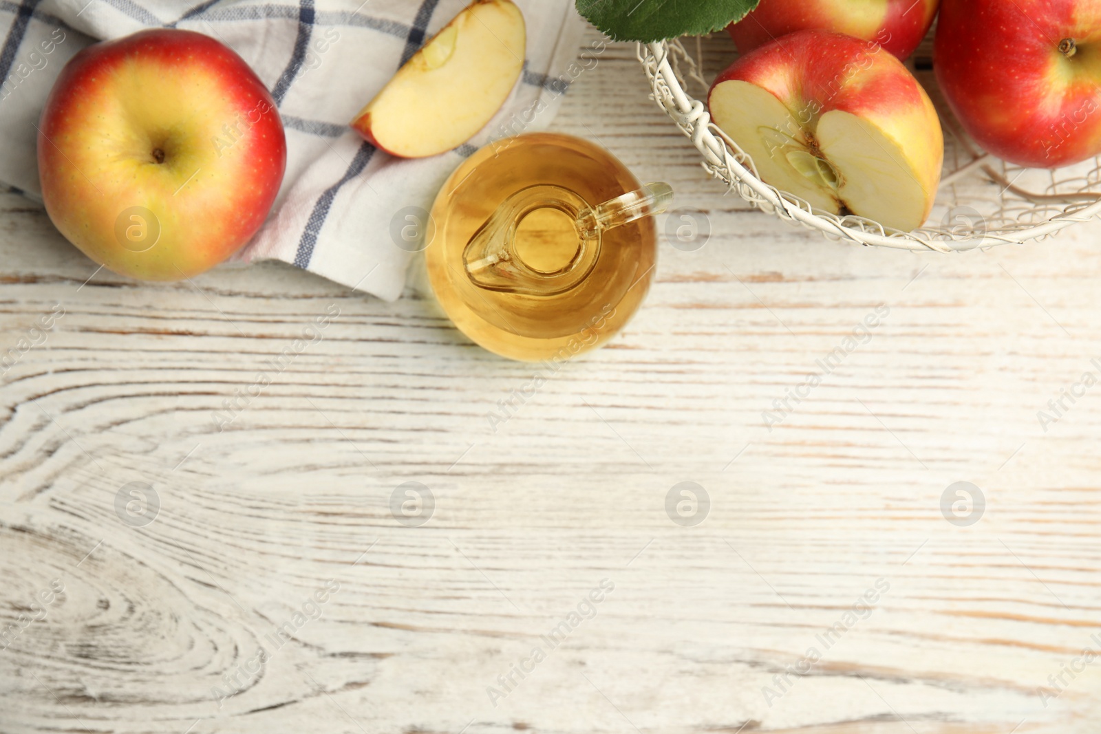 Photo of Natural apple vinegar and fresh fruits on white wooden table, flat lay. Space for text