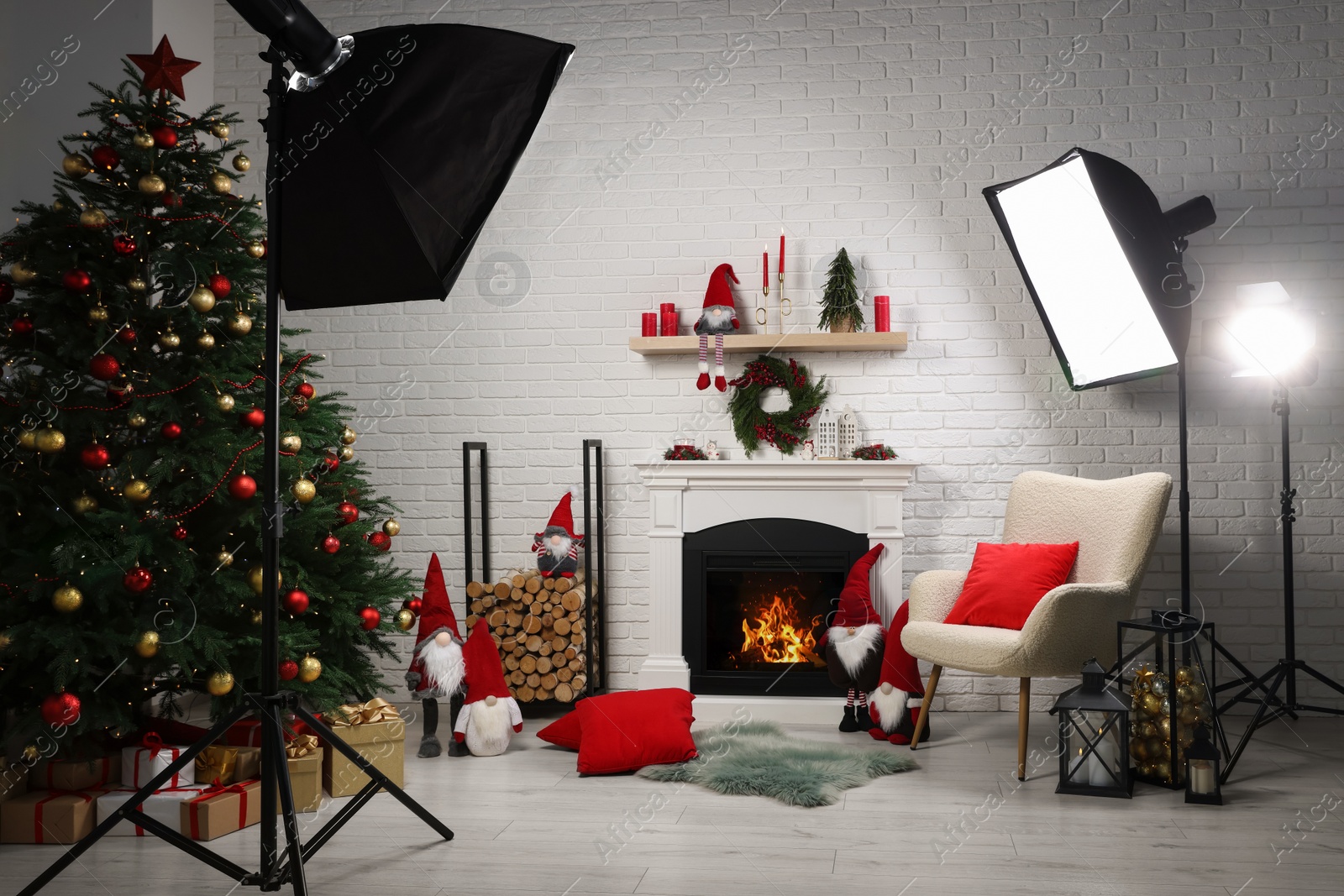 Photo of Beautiful Christmas themed photo zone with professional equipment, tree and fireplace in room