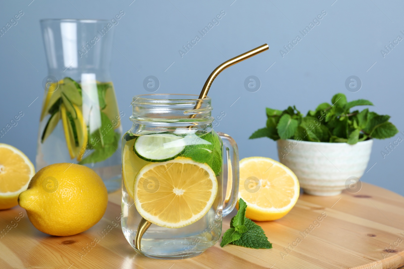 Photo of Refreshing water with cucumber, lemon and mint on wooden table