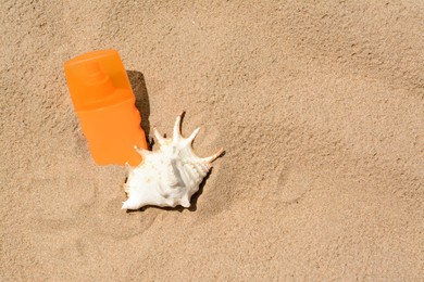 Photo of Bottle with sun protection spray and seashell on sandy beach, space for text