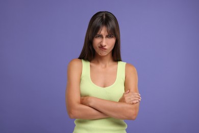 Photo of Resentful woman with crossed arms on violet background
