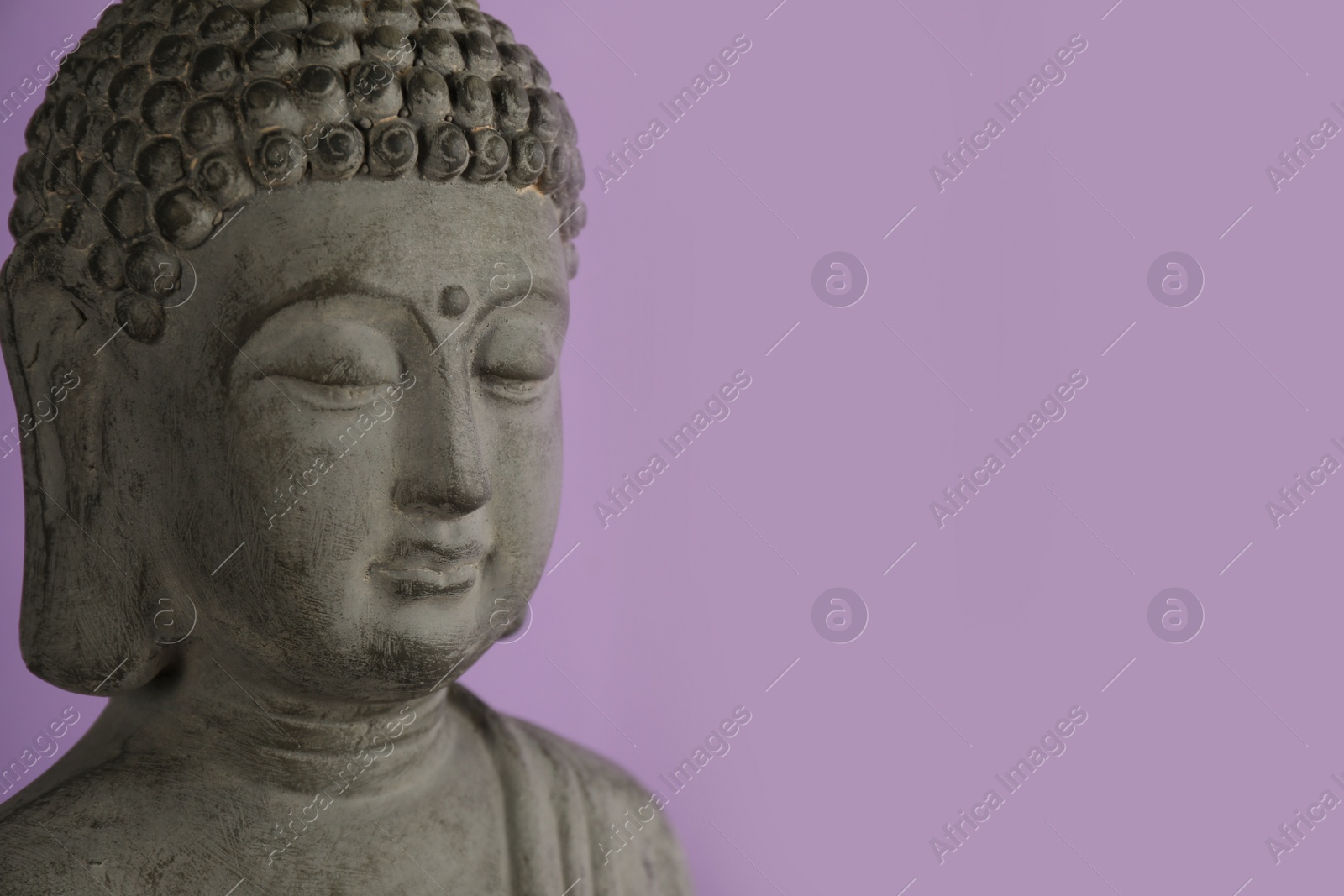 Photo of Beautiful stone Buddha sculpture on violet background, closeup. Space for text