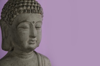 Beautiful stone Buddha sculpture on violet background, closeup. Space for text