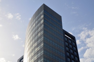 Photo of Exterior of beautiful modern skyscraper against blue sky, low angle view