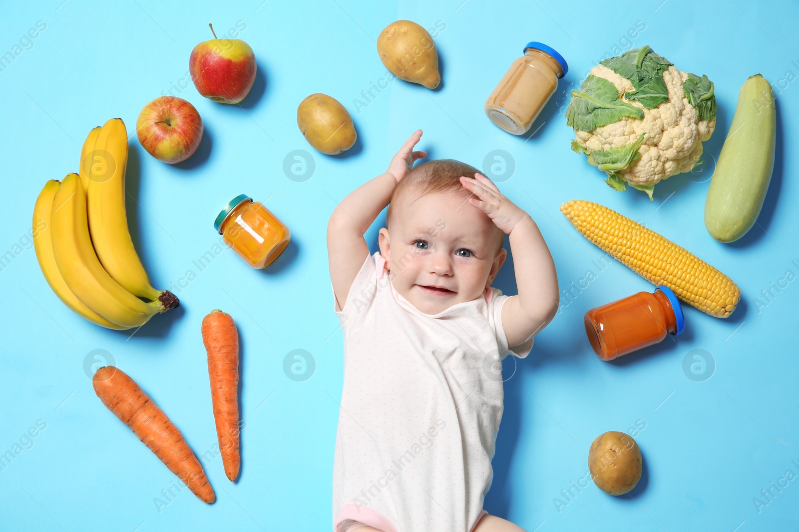 Photo of Cute little child with ingredients and purees in jars on color background, top view. Baby food