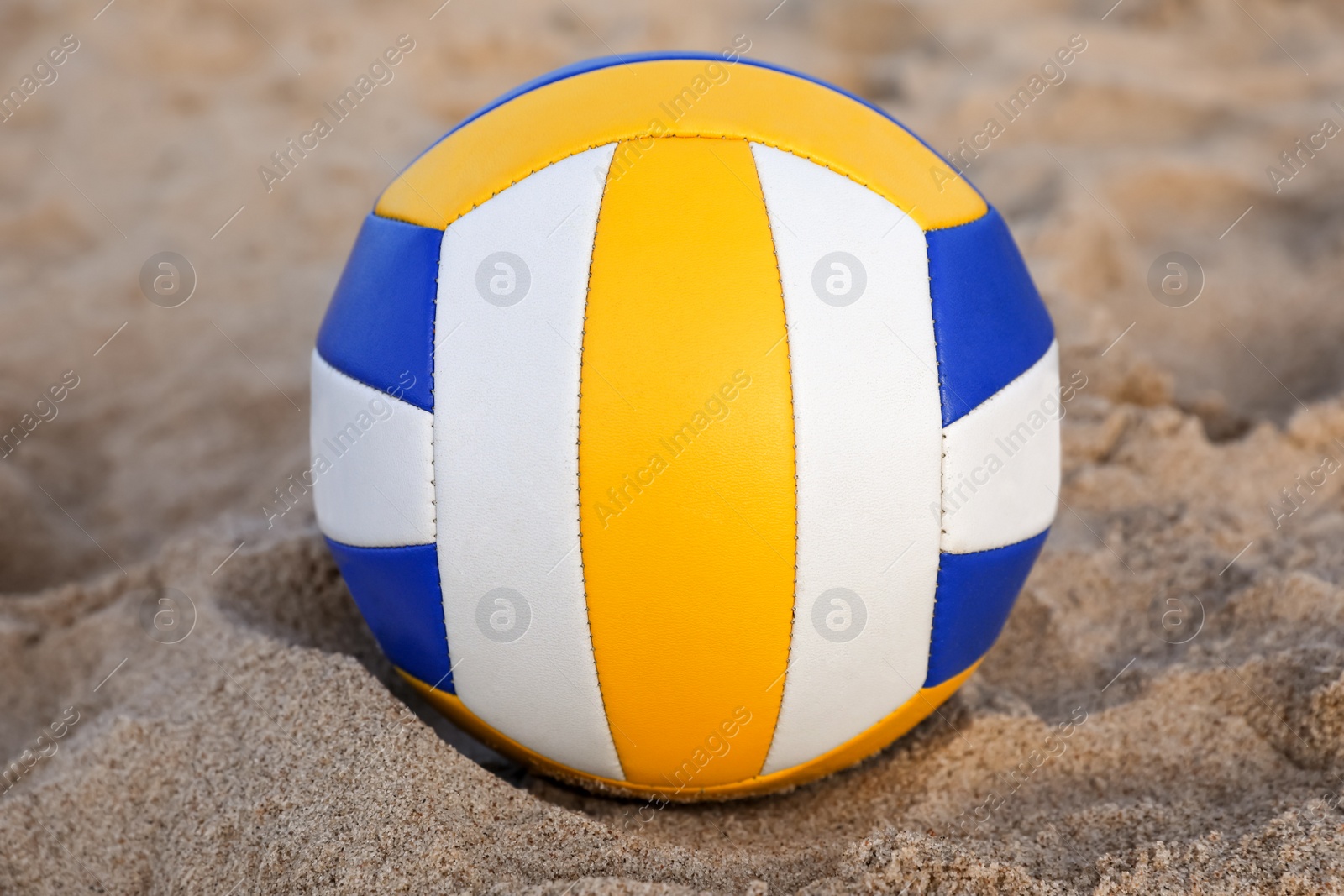 Photo of Colorful volleyball ball on sandy beach, closeup