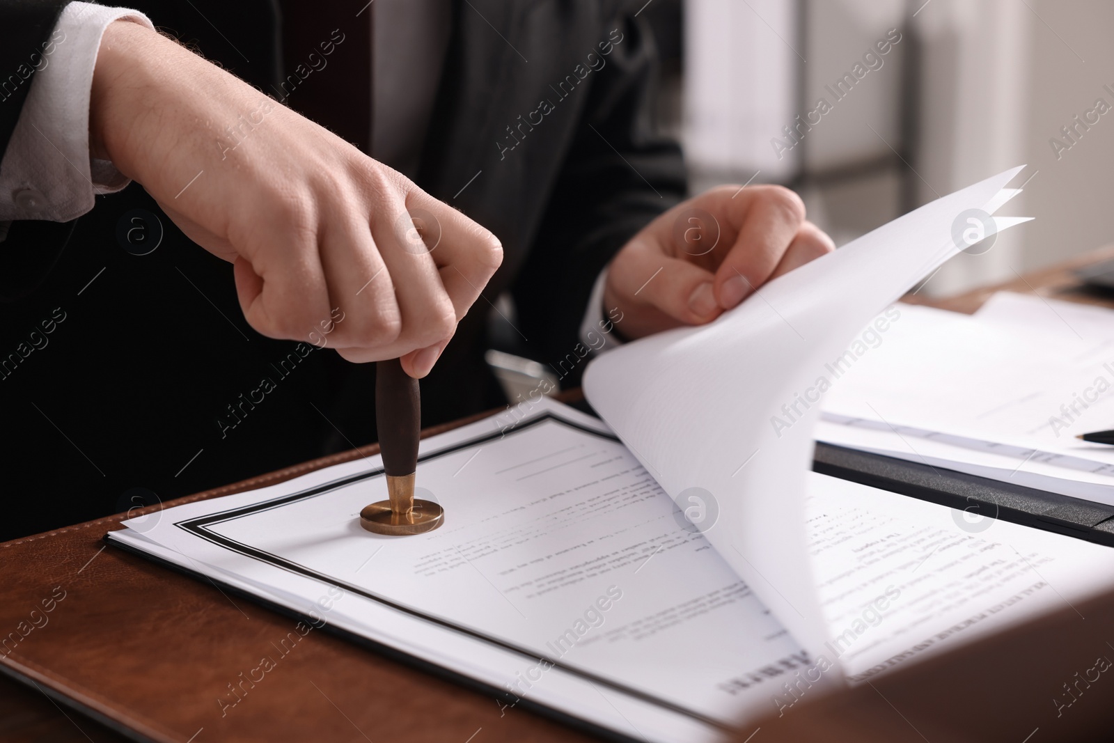 Photo of Notary stamping document at table in office, closeup