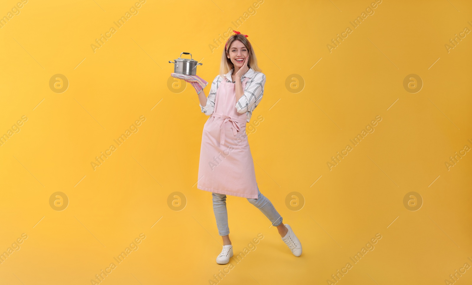 Photo of Young housewife with pot on yellow background