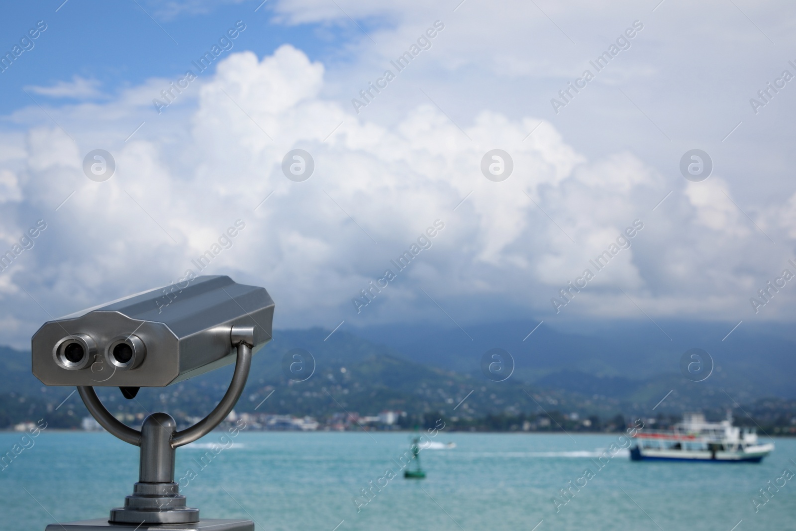 Photo of Metal tower viewer installed near sea, space for text. Mounted binoculars